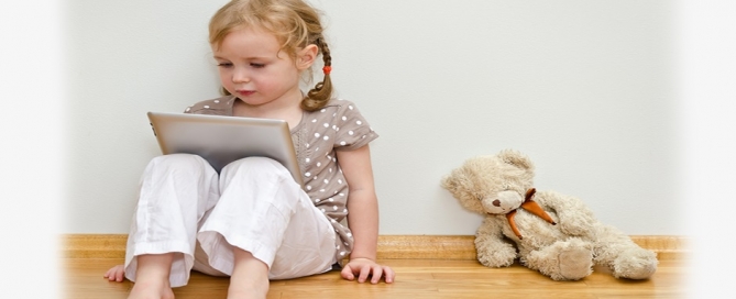Cute little girl reading on an ipad with bear
