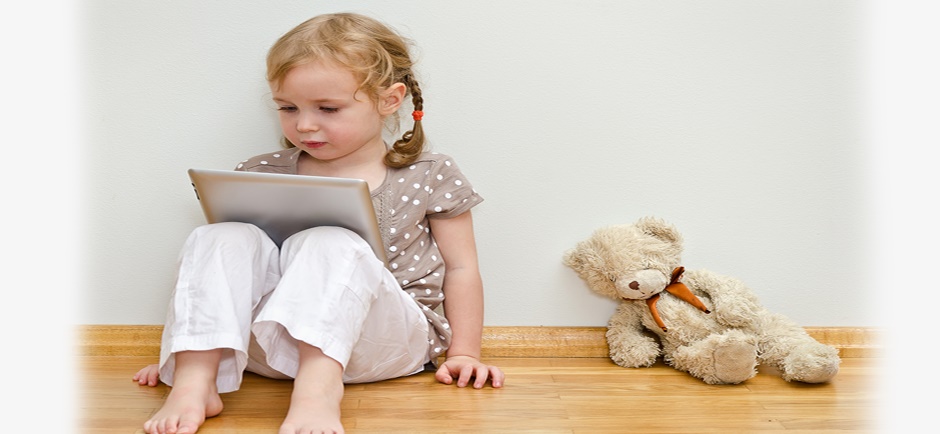 Cute little girl reading on an ipad with bear